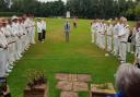 The two teams in the Philip Gillet memorial match at Waresley Cricket Club listen to a speech from John Gillett.