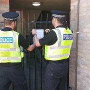 Police officers putting up the closure order notice at the property