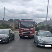 The fire engine nearly got stuck in between two cars.