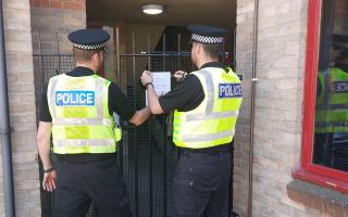 Police officers putting up the closure order notice at the property